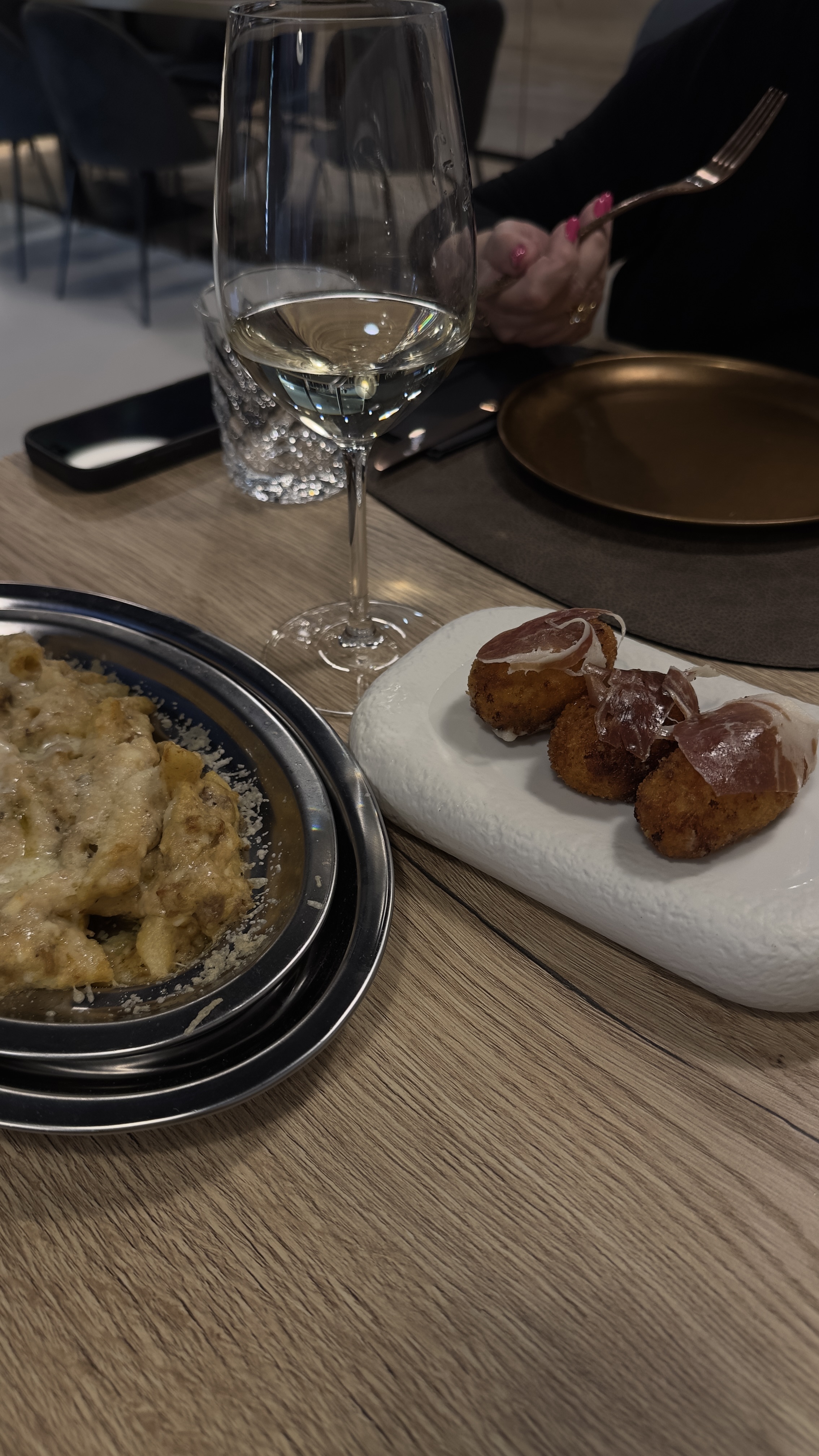 Taula amb plats per compartir i copa de vi