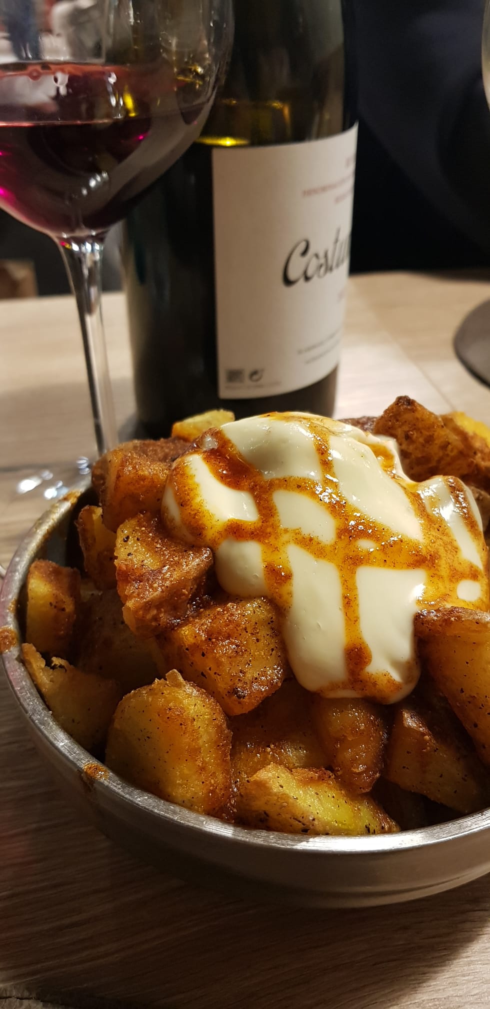Patates braves amb una ampolla de vi al fons